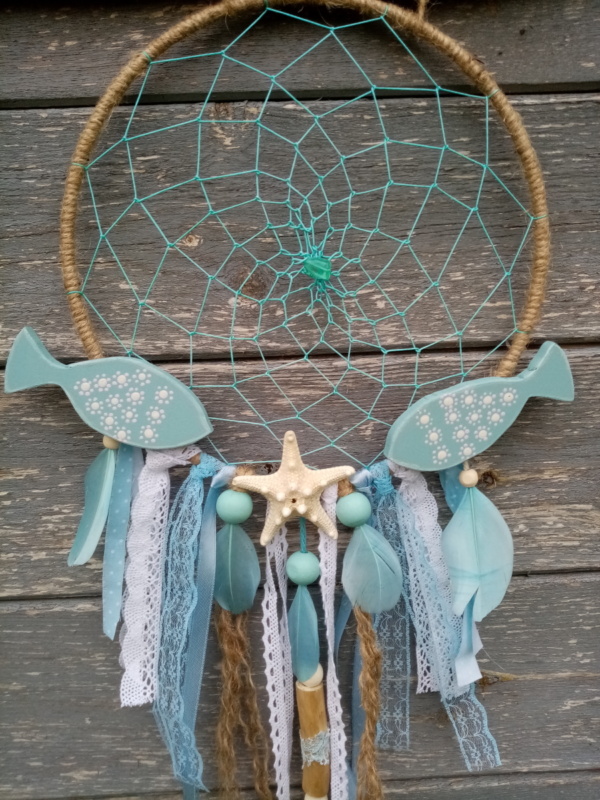 Deux petits poissons en bois chantournés et patinés avec étoile de mer posés sur attrape rêve thème bleu